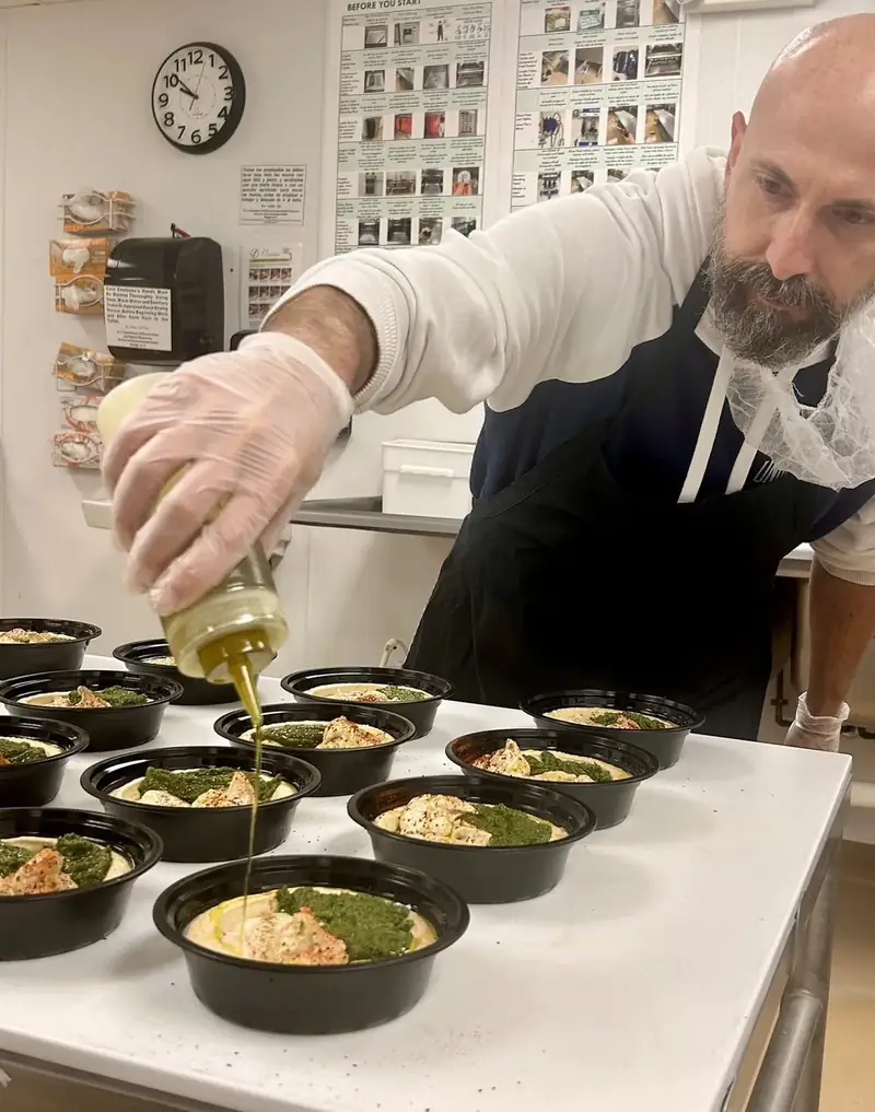 Alon finishing a tray of schug bowls with olive oil