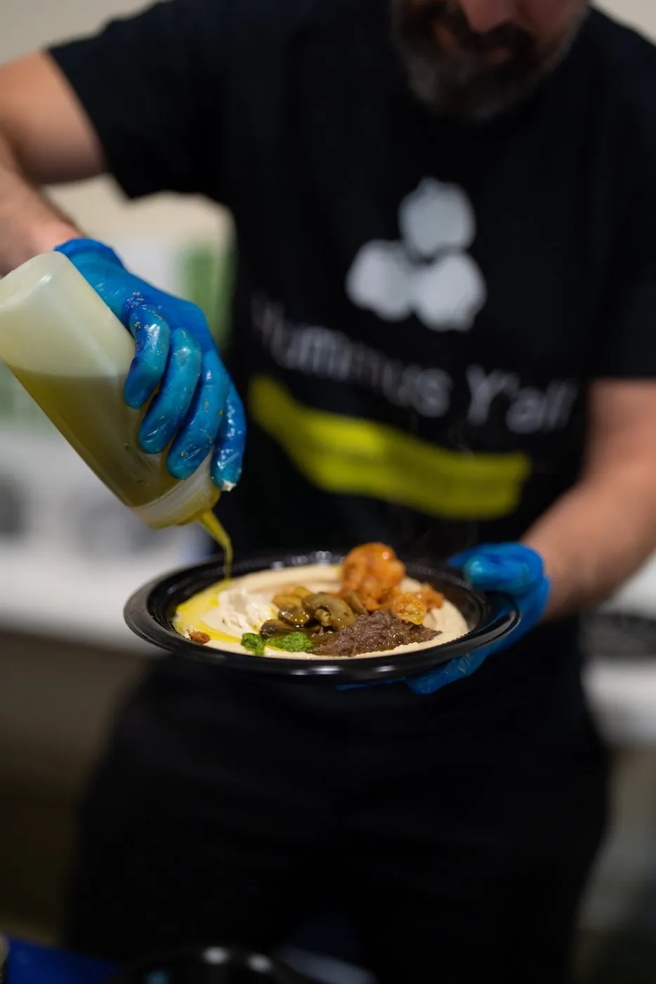 Olive oil being drizzled over a hummus bowl