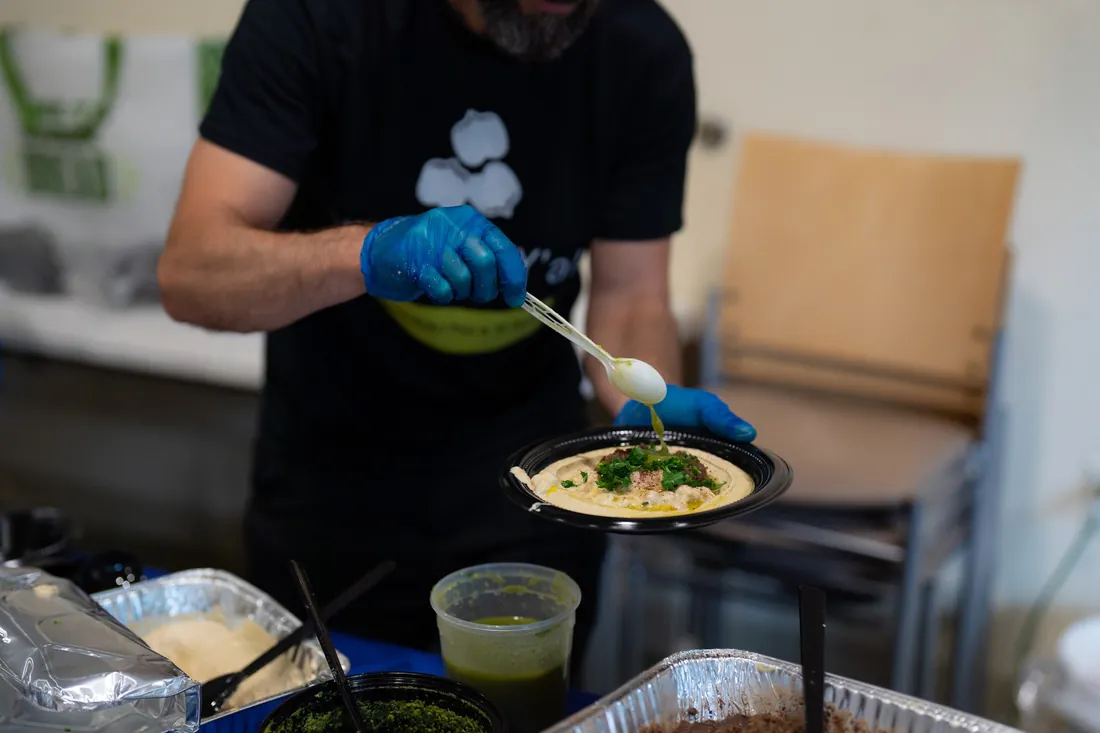 Alon plating a hummus bowl at a live hummus station