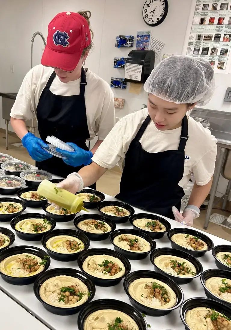 The team plating chickpea bowls in the kitchen